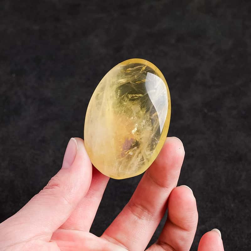 "Polished Citrine palm stone, warm golden-yellow translucent crystal on palm — manifestation stone for wealth and joy"