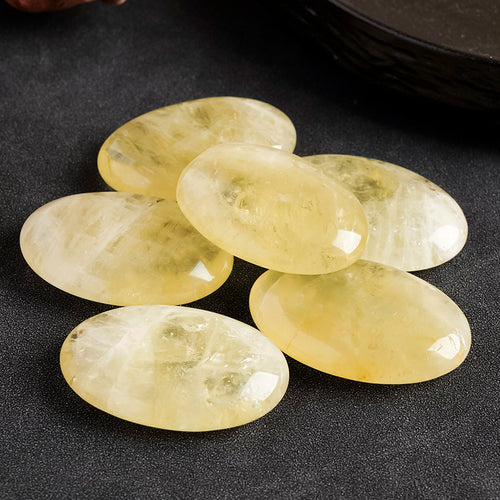 "Polished Citrine palm stone, warm golden-yellow translucent crystal on palm — manifestation stone for wealth and joy"
